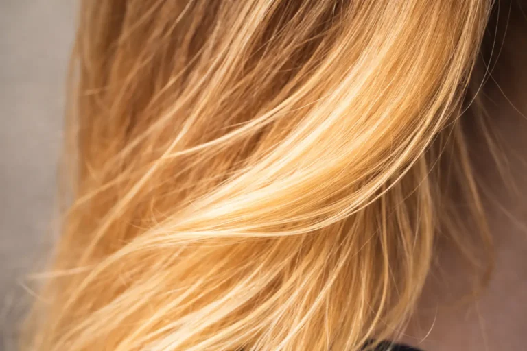 Gros plan de cheveux éclaircis naturellement avec reflets dorés au soleil, illustrant un éclaircissement progressif sans décoloration.
