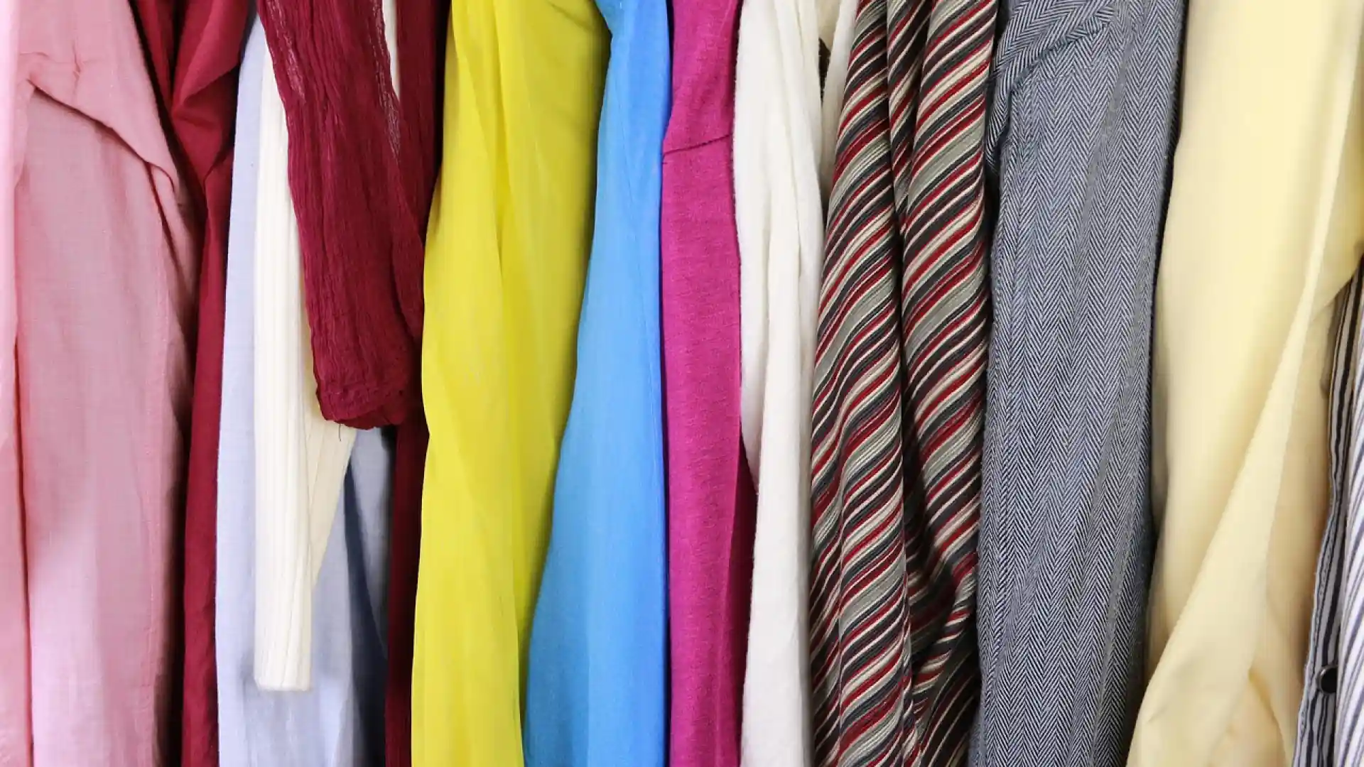 Vêtements colorés suspendus dans une penderie avec chemises, vestes et cravates